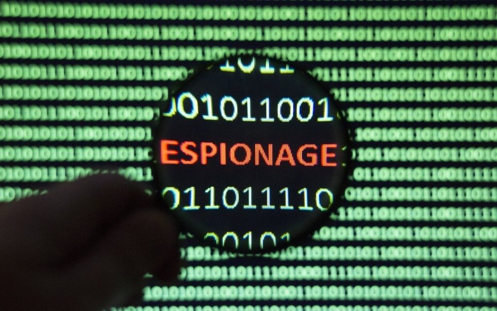 Słowo espionage widoczne przez lupę na tle zielonego kodu binarnego, symbolizujące cyberbezpieczeństwo