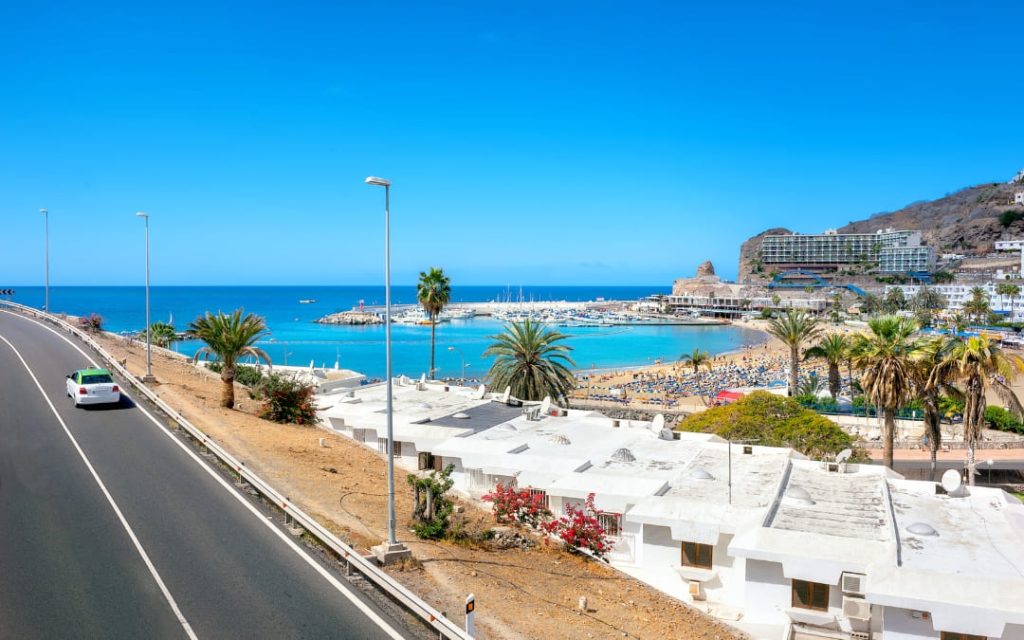 Widok na plażę Playa de Puerto Rico, marinę, palmy i turkusową zatokę w kurorcie Puerto Rico de Gran Canaria