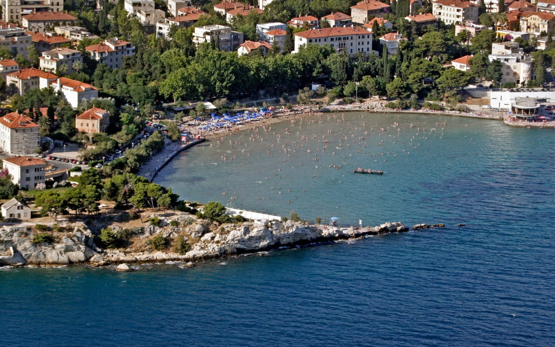 Widok z góry na plażę Bačvice w Splicie z półkolistą zatoką, kąpiącymi się osobami i zabudową miasta w tle