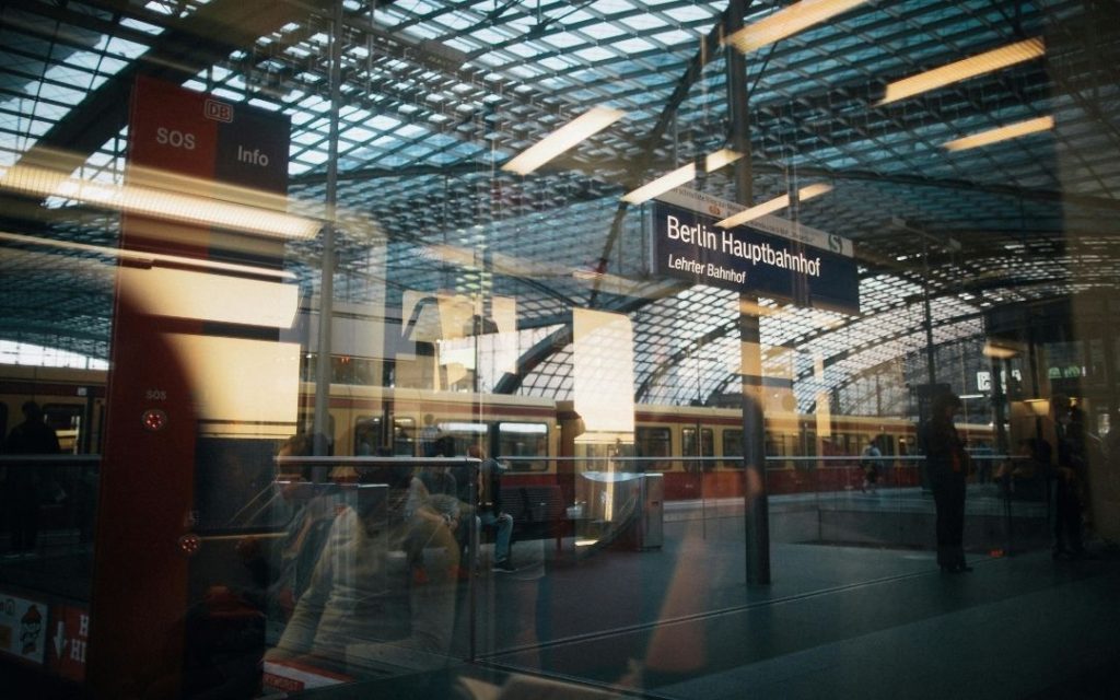 Widok z pociągu na Berlin Hauptbahnhof z widocznym znakiem i ludźmi