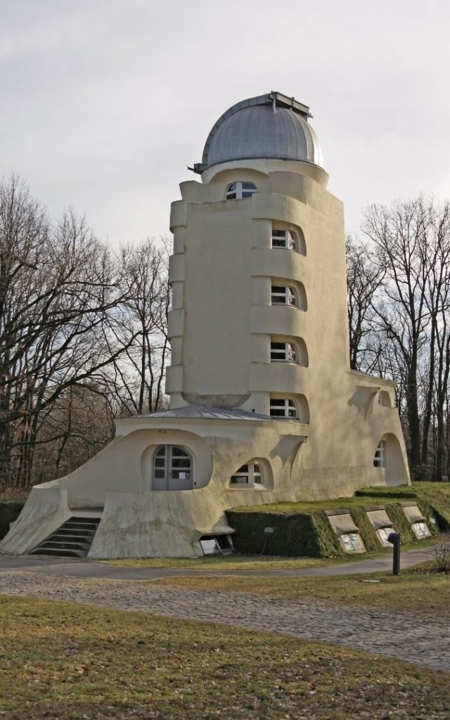 Wieża Einsteina w Poczdamie z kopułą obserwatorium, parkową alejką i drzewami w tle

