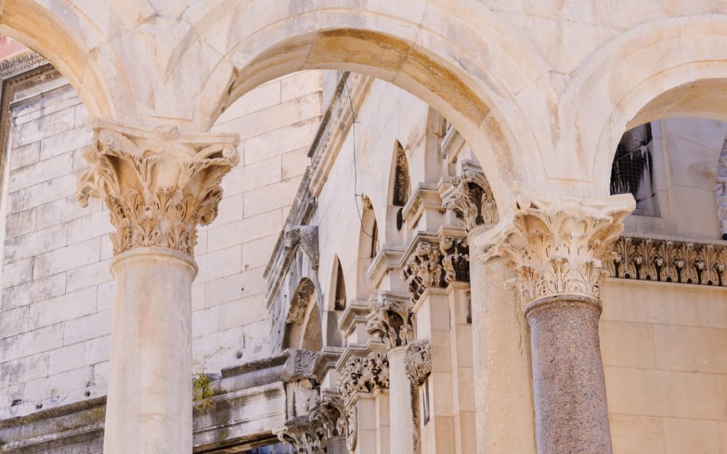 Zabytkowe kamienne arkady wsparte na ozdobnych kolumnach z bogato rzeźbionymi kapitelami, stanowiące charakterystyczny element historycznej architektury