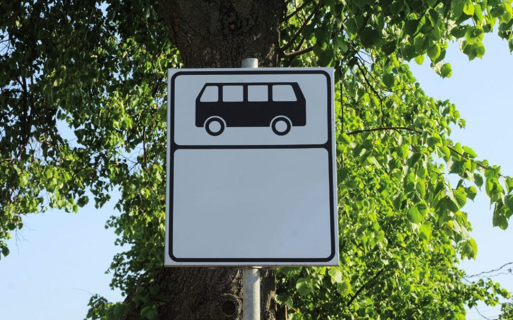 Znak przystanku autobusowego na tle zielonych drzew