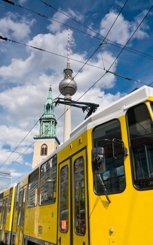 Żółty tramwaj w Berlinie z widokiem na Fernsehturm i Kościół Mariacki