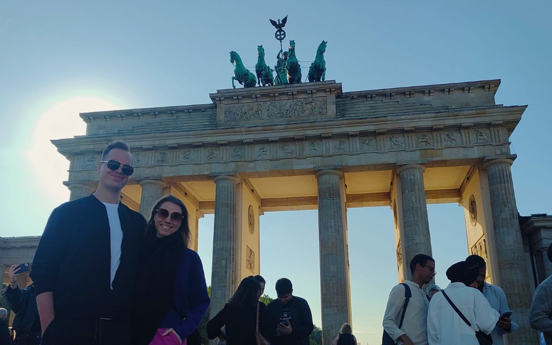 osoby pozujące przed Bramą Brandenburską w Berlinie, z Kwadrygą na szczycie i turystami wokół zabytkowego monumentu