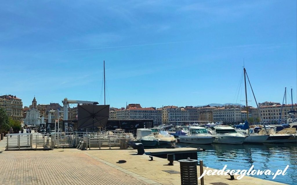 Stary Port w Marsylii z zacumowanymi jachtami, spacerującymi turystami i widokiem na miasto