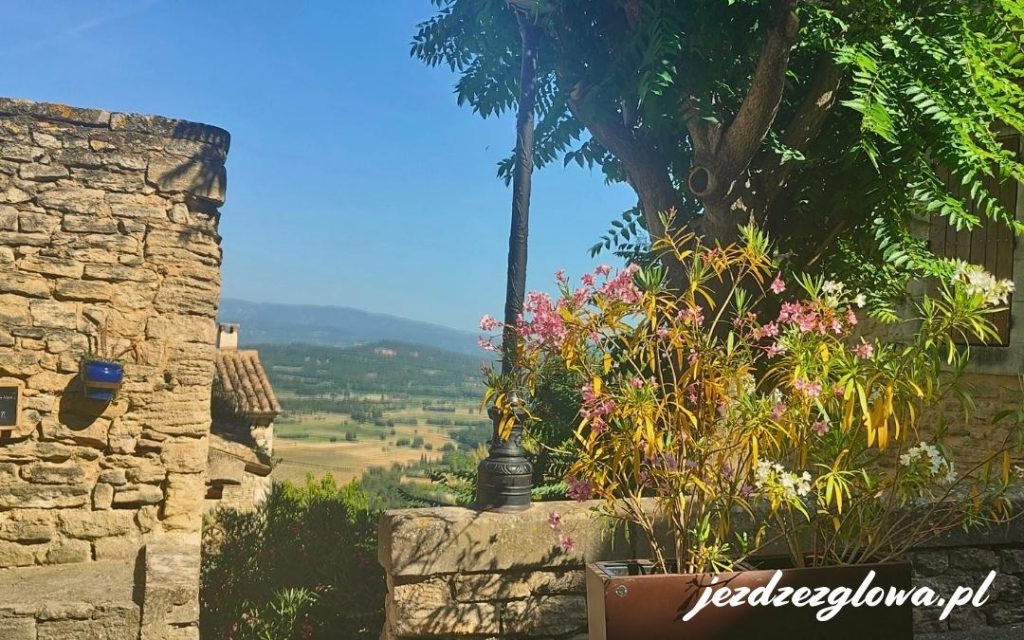Taras w Gordes – kwitnące oleandry, kamienne mury i widok na dolinę Luberon