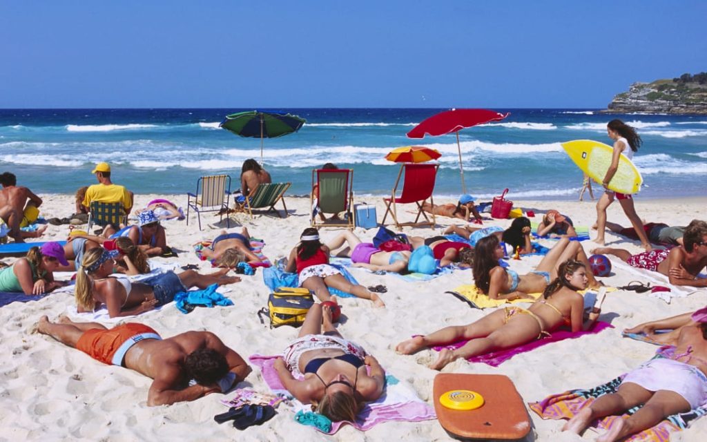 Turyści opalający się na piaszczystej plaży nad oceanem
