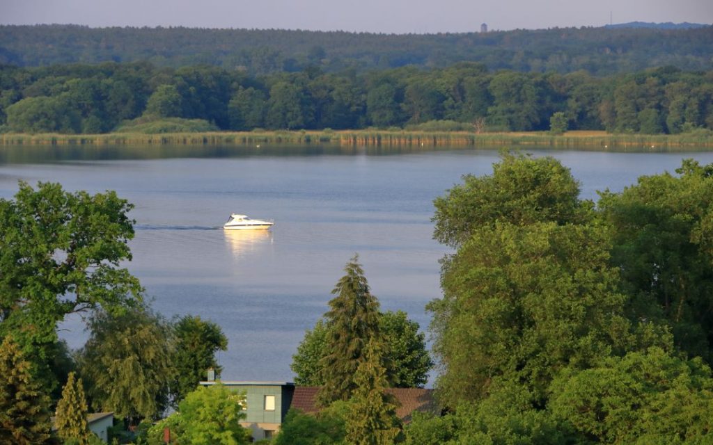 Widok na jezioro w Werder nad Hawelą z płynącą łodzią i leśną panoramą