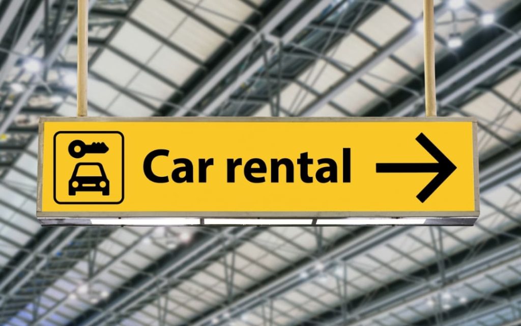 Żółta tablica car rental ze strzałką kierującą do wypożyczalni aut