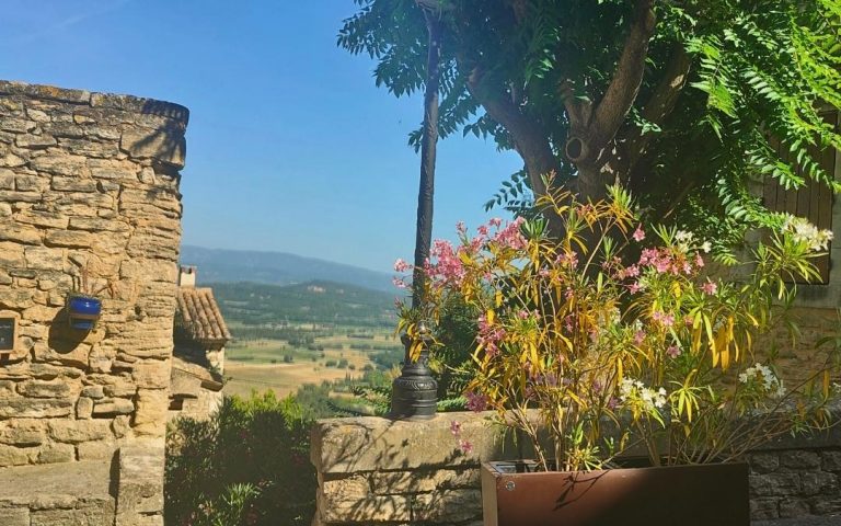 Taras w Gordes – kwitnące oleandry, kamienne mury i widok na dolinę Luberon